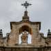 Il coronamento presenta dei pinnacoli ai lati e un fastigio a baldacchino che racchiude una statua della Madonna in gloria con angeli